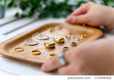 Various gold and silver rings and accessories displayed on a wooden tray Various gold and silver rings and accessories displayed on a wooden tray 133866068