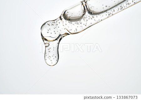 Cosmetic pipette dripping clear serum fluid with bubbles 133867073