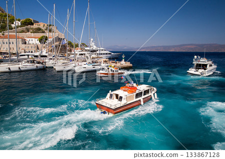 Awe  view on Boat - water taxi   at  island with harbor with ssailboats behind.   Hydra island  - best of Greek islands 133867128