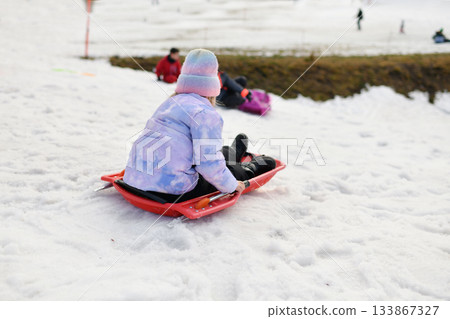 A girl with snow bob sledding in the snow A girl with snow bob sledding in the snow 133867327