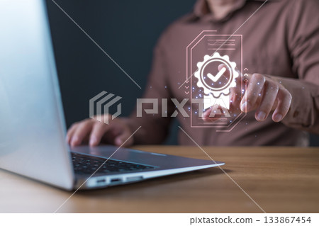 A businessman interacts with a glowing digital icon of a certificate featuring a checkmark, symbolizing quality assurance and trust in digital standards, service, or performance. A businessman interacts with a glowing digital icon of a certificate featuring a checkmark, symbolizing quality assurance and trust in digital standards, service, or performance. 133867454