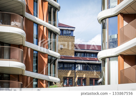 Modern Residential Buildings Framing a Traditional Brick Structure Under Bright Sky Modern Residential Buildings Framing a Traditional Brick Structure Under Bright Sky 133867556