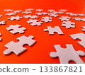 The image shows several pieces of a jigsaw puzzle on a orange background. 133867821