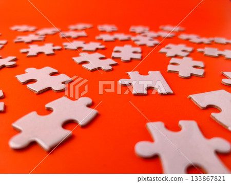 The image shows several pieces of a jigsaw puzzle on a orange background. The image shows several pieces of a jigsaw puzzle on a orange background. 133867821