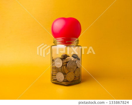 A red, heart-shaped object on top of the jar could symbolize saving for health, love, or personal goals. A red, heart-shaped object on top of the jar could symbolize saving for health, love, or personal goals. 133867824
