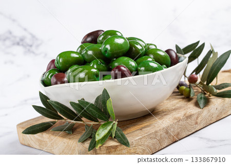 Chalkidiki olives, classic Greek green olives, in a bowl on a cutting board, top view, without people, 133867910