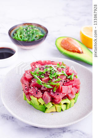 Fresh tuna tartare with avocado served on a marble table with soy sauce and seaweed salad 133867928