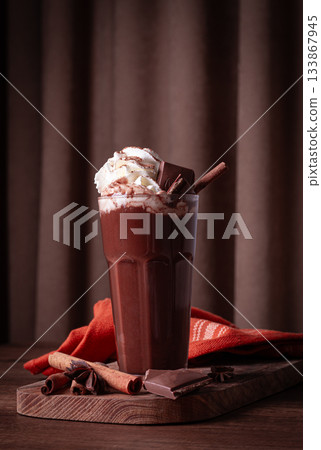 hot chocolate drink, topped with whipped cream, chocolate shavings, and a cinnamon stick hot chocolate drink, topped with whipped cream, chocolate shavings, and a cinnamon stick 133867945