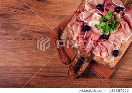 sliced prosciutto, on a cutting board, with olives and herbs, snack, breakfast, no people, sliced prosciutto, on a cutting board, with olives and herbs, snack, breakfast, no people, 133867952
