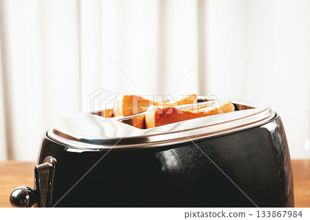 Toast is browning in a metal toaster in a kitchen setting during breakfast time Toast is browning in a metal toaster in a kitchen setting during breakfast time 133867984