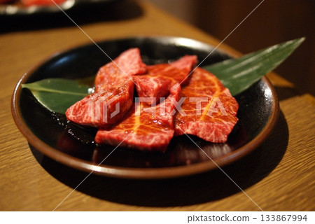 一盤奢華的黑色盤子，盛著紋理清晰的瘦肉，以稻草和竹子裝飾。 133867994