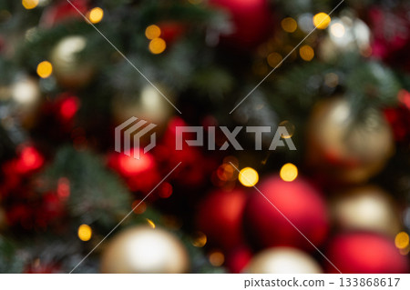 Blurred Christmas tree with red balls and lights garland. Abstract pattern. Defocused background. Xmas holiday spirit. Blurred Christmas tree with red balls and lights garland. Abstract pattern. Defocused background. Xmas holiday spirit. 133868617