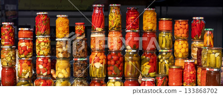 Colorful jars of pickled vegetables line a market stall with vibrant preserves 133868702