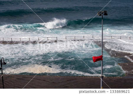 Red flag on the Atlantic ocean beach, Tenerife, Spain Red flag on the Atlantic ocean beach, Tenerife, Spain 133869621