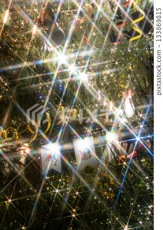 Christmas tree with yellow ribbon, toys. Christmas tree decorated with garlands lots of sparkles.  133869815