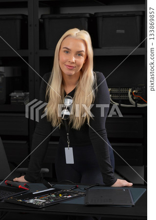 Young woman IT technician repairs and toils at open laptop in server room for hardware upgrade and troubleshooting 133869857