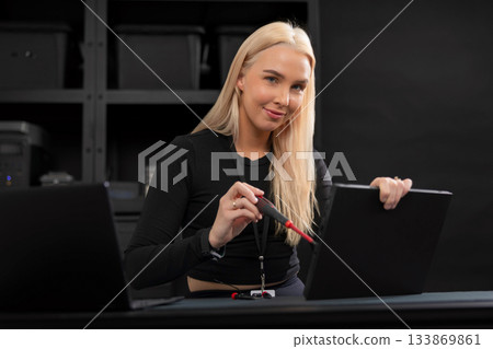 Female IT technician with laptop performing maintenance and repair in a modern tech workspace 133869861