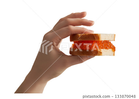 Hand holding delicate red caviar sandwich canape, appetizer for events, luxury dining and celebration 133870048