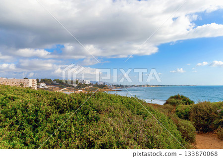 Sicily Italy seascape overlooking turquoise bay and faraway resort skyline. 133870068