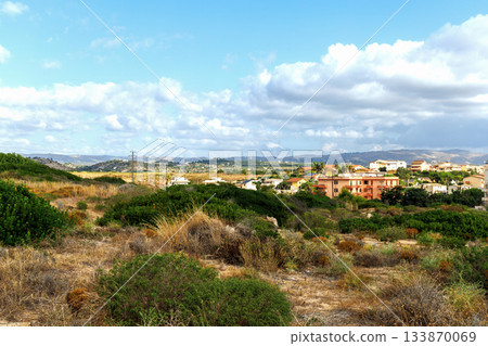Sunny Sicily countryside settlement with colorful homes and mountain horizon view. 133870069