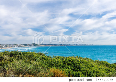 Aerial view of Sicilian coastline with turquoise bay and distant resort 133870076