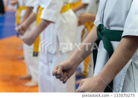A line of children in white karate uniforms with yellow and green belts A line of children in white karate uniforms with yellow and green belts 133870275