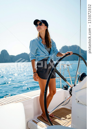 Sailor Enjoys Steering a Yacht Against a Serene Blue Seascape on a Sunny Afternoon in Summer Sailor Enjoys Steering a Yacht Against a Serene Blue Seascape on a Sunny Afternoon in Summer 133872832