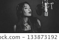 Young woman sings passionately into microphone in studio setting during night 133873192