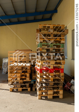 Stacks of wooden pallets are stored in an industrial warehouse yard 133873246