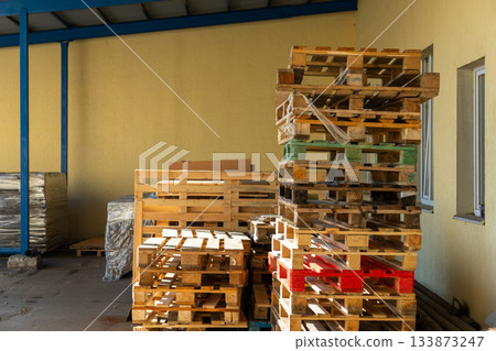 Stacks of wooden pallets are stored in an industrial warehouse yard Stacks of wooden pallets are stored in an industrial warehouse yard 133873247