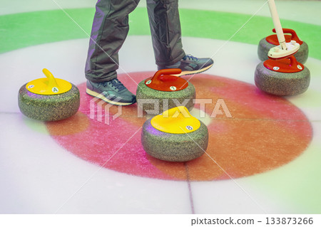 Feet of curling players near stones during strategic winter sports moment on ice. Concept of curling accuracy, close score and final round tension 133873266