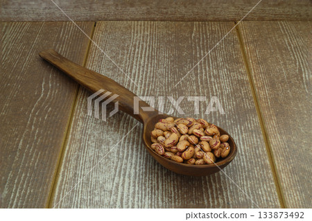 red kidney beans in wooden spoon isolated on dark background. red kidney beans in wooden spoon isolated on dark background. 133873492