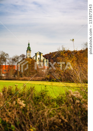 Historic Fuerstenfeldbruck Monastery In Bavaria: Baroque Church Tower Rising Above Autumn Trees And Open Green Fields Under Soft Daylight Historic Fuerstenfeldbruck Monastery In Bavaria: Baroque Church Tower Rising Above Autumn Trees And Open Green Fields Under Soft Daylight 133873543