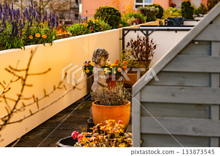 Terrace Garden With Flower Pots And Stone Statue: Sunlit Outdoor Arrangement Of Colorful Blossoms And Decorative Sculpture In Warm Autumn Atmosphere Terrace Garden With Flower Pots And Stone Statue: Sunlit Outdoor Arrangement Of Colorful Blossoms And Decorative Sculpture In Warm Autumn Atmosphere 133873545