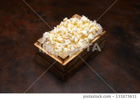 popcorn in a small wooden crate, isolated on dark background. popcorn in a small wooden crate, isolated on dark background. 133873631