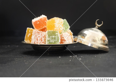 Turkish delight dessert in plate on black background Turkish delight dessert in plate on black background 133873646