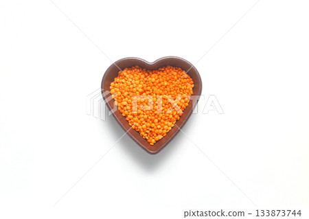 Pile red lentil in shape of heart isolated on white background. Top view. Flat lay. Pile red lentil in shape of heart isolated on white background. Top view. Flat lay. 133873744
