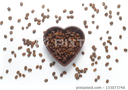 Roasted coffee beans in heart shaped bowl on white background. Love coffee concept. Top view flat lay with copy space Roasted coffee beans in heart shaped bowl on white background. Love coffee concept. Top view flat lay with copy space 133873748