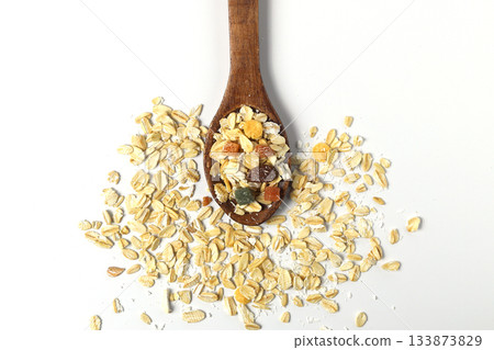 Breakfast cereals in wooden spoon. Healthy muesli with oat flakes, nuts and raisins isolated on white background. Breakfast cereals in wooden spoon. Healthy muesli with oat flakes, nuts and raisins isolated on white background. 133873829