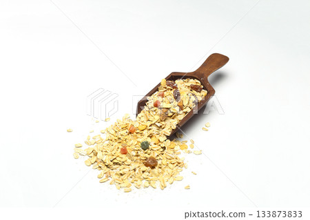 Breakfast cereals in wooden spoon. Healthy muesli with oat flakes, nuts and raisins isolated on white background. 133873833