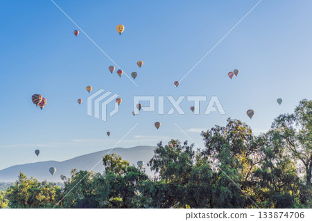 Colorful hot air balloons floating over Teotihuacan in Mexico, creating a breathtaking view of the ancient pyramids. Tourism, adventure, and cultural heritage concept Colorful hot air balloons floating over Teotihuacan in Mexico, creating a breathtaking view of the ancient pyramids. Tourism, adventure, and cultural heritage concept 133874706