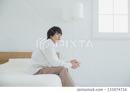 A young man sitting in bed A young man sitting in bed 133874716