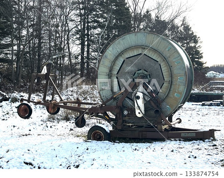 Old agricultural sprinkler machine on the snow 133874754