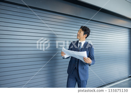 A businessman thinking in front of a store property 133875130