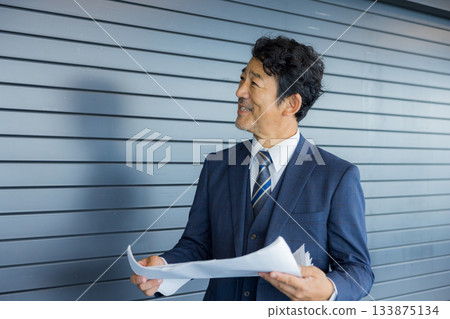 A businessman thinking in front of a store property 133875134