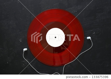 White headphones with wire and Red vinyl discs on an black background. Retro technique for playing music. 133875396