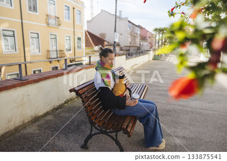 Tranquil urban moment capturing woman in scarf drinking coffee leisurely 133875541