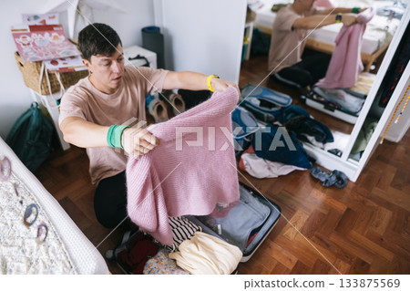 young asian man packing pink sweater as thoughtful gift young asian man packing pink sweater as thoughtful gift 133875569