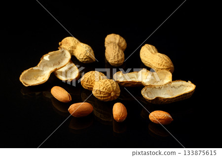 Peanut on glossy black surface with reflection. Group of peanuts isolated on black backgrounds Peanut on glossy black surface with reflection. Group of peanuts isolated on black backgrounds 133875615