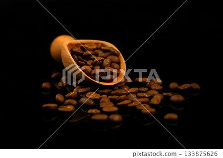 Coffee beans in a wooden scoop isolated on a black background. Roasted coffee beans isolated. 133875626